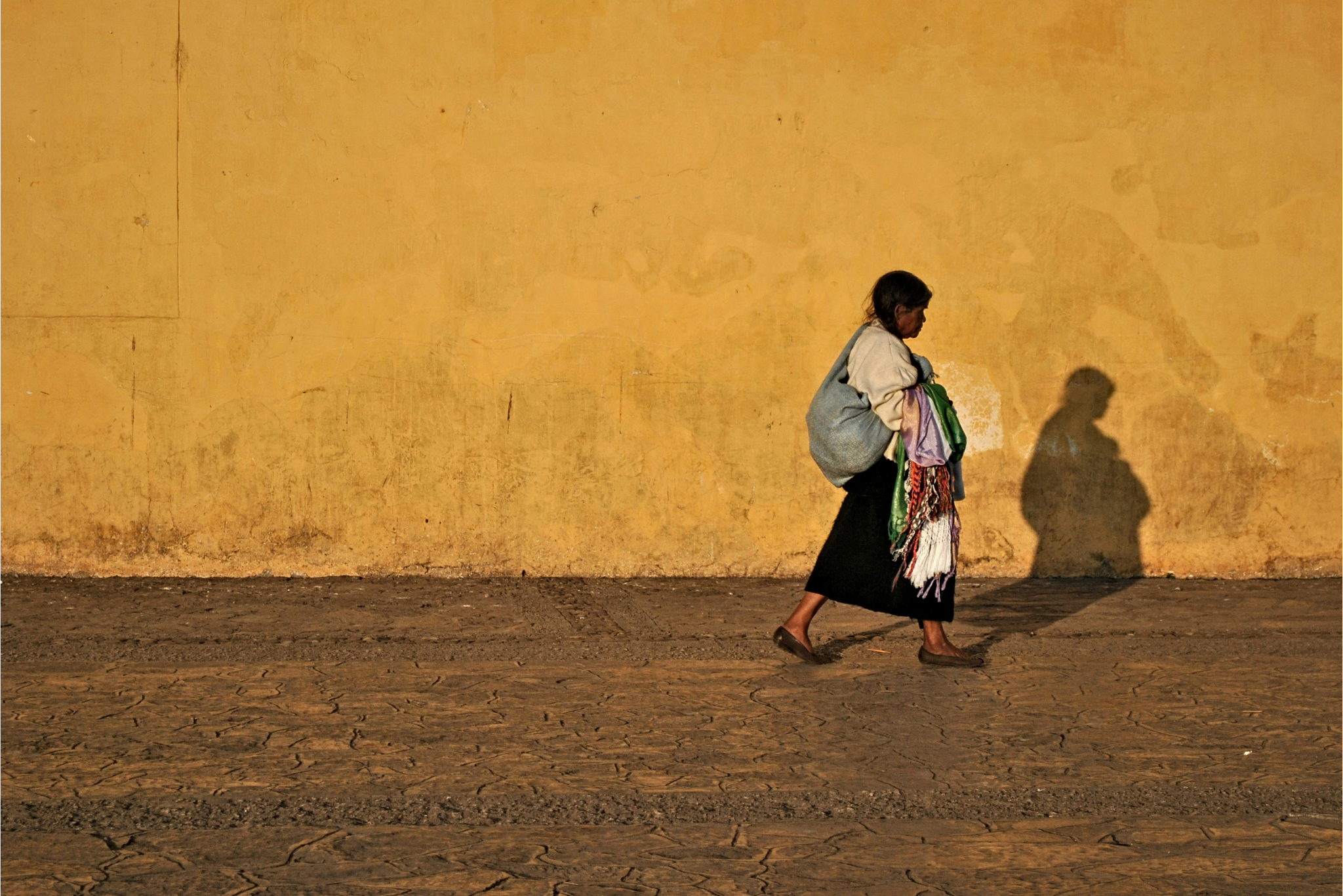 Donna cammina lungo un muro ocra al tramonto